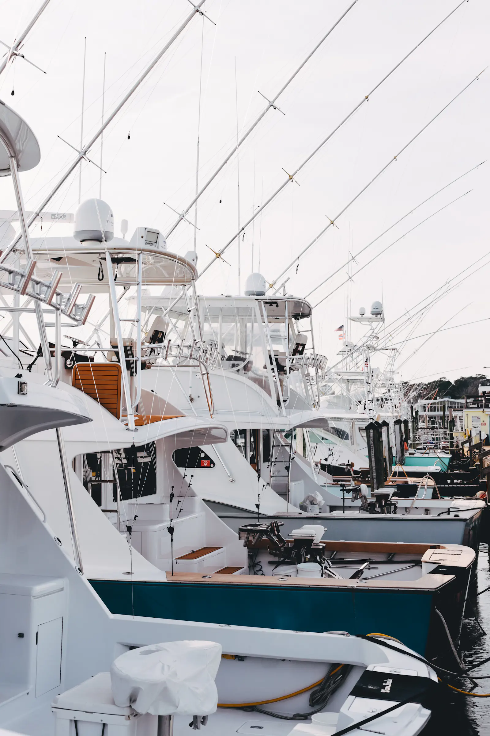 A row of sportfishing convertibles docked with outriggers raised